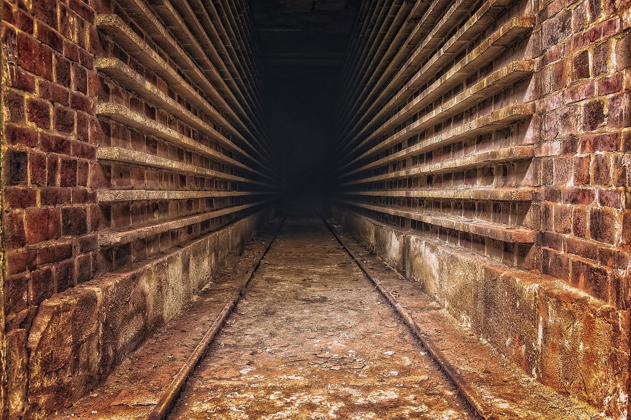 Underground tunnel with brick walls and railway tracks, symbolizing pathways and progress in healthc.