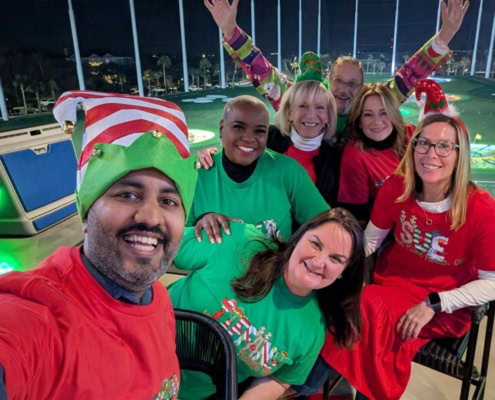 Festive team gathering at VitalCaring celebrating Christmas with joyful smiles and holiday attire.