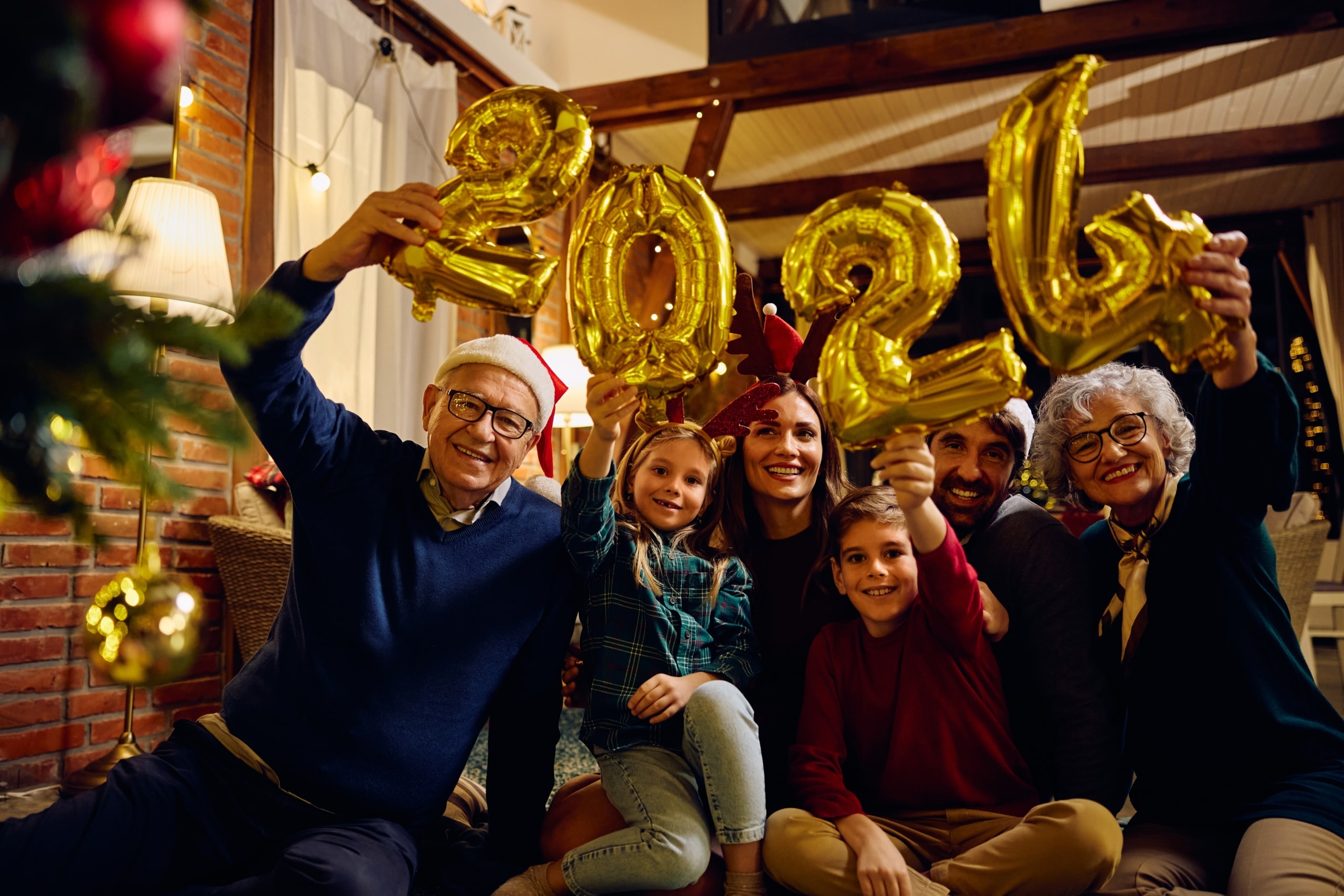 Happy family celebrating New Year with golden "2024" balloons at home.