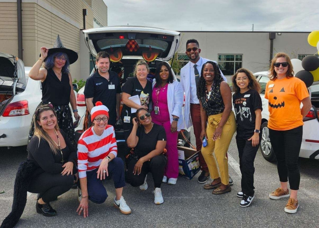 Group of people celebrating Halloween with decorated cars and costumes.
